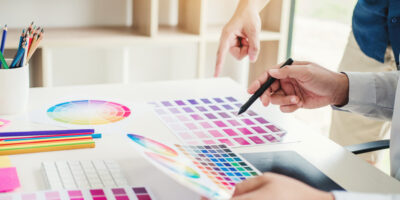 Graphic designer drawing on graphics tablet at workplace Drucker wählen Farben aus.